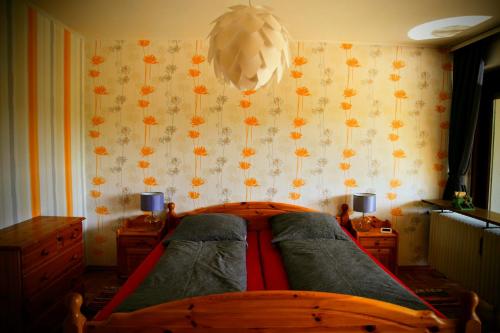 1 dormitorio con 1 cama y una pared con flores en Ferienwohnung Rhododendron - Natur pur Kinderparadies, en Rotenburg an der Fulda
