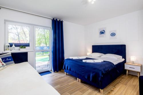 a bedroom with a blue bed and a window at Apartament 2B Blue Marine Poddąbie in Poddąbie