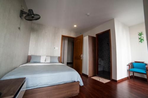 a bedroom with a large bed and a blue chair at Tre Việt Tuy Hòa Hotel in Tuy Hoa