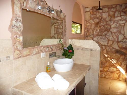 a bathroom with a sink and a stone wall at Mundo Milo Eco Lodge in Playa Junquillal