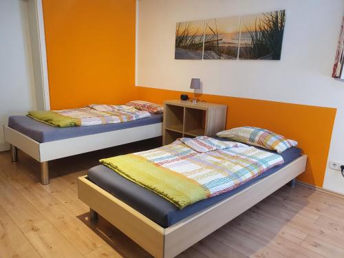 2 Betten in einem Zimmer mit orangefarbenen Wänden in der Unterkunft Ferienwohnung Monteurwohnung Landshut in Vilsheim