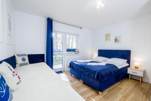a bedroom with a blue bed and a window at APARTAMENT 9B BLUE MARINE Poddąbie Basen Odkryty Brodziki Plac Zabaw in Poddąbie