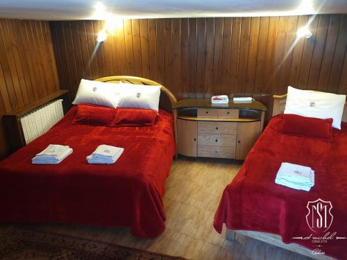 a bedroom with two beds with red sheets and a table at Saint Michel Chalets in Al Arz