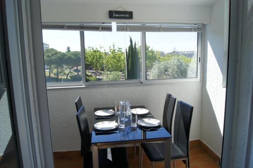 une salle à manger avec une table et des chaises et une fenêtre dans l'établissement Lara 3 - T2 Loggia Piscine 2 lits doubles Parking Près du centre-port et île Loisirs, au Cap d'Agde