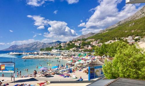 a beach with a bunch of people in the water at Apartmani Zuzana in Baška Voda