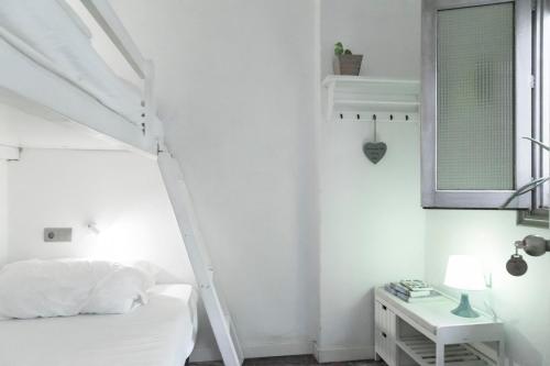 
a bedroom with a white bed and a white wall at La Cocotera Boutique Hostel & Coworking in Tarifa
