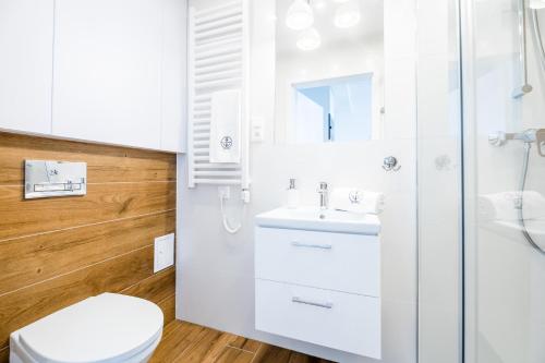 biała łazienka z toaletą i umywalką w obiekcie APARTAMENT 19B BLUE MARINE Poddąbie Basen Odkryty Brodziki Plac Zabaw w Poddąbiu