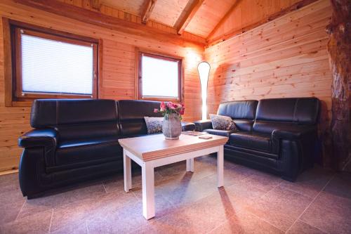a living room with black leather furniture and a table at Brvnara Aurora Vista in Velika Remeta