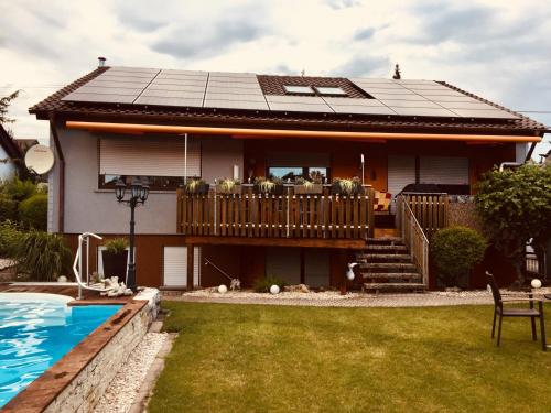 a house with a solar roof and a swimming pool at Ferienwohnung Schwarz in Sersheim