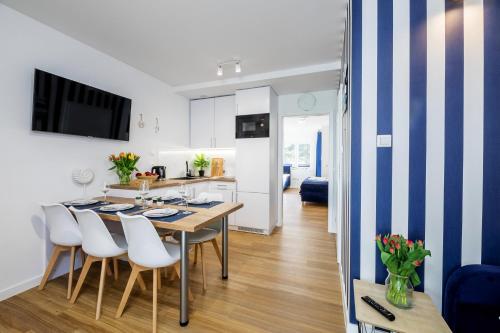 a kitchen and dining room with a table and chairs at APARTAMENT 17B BLUE MARINE Poddąbie Basen Odkryty Brodziki Plac Zabaw in Poddąbie