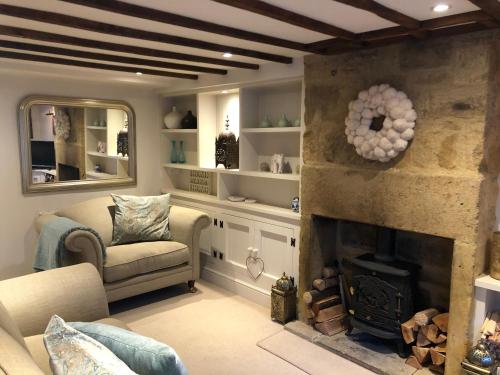 a living room with a fireplace and a chair at Cottage in the heart of Montacute in Montacute