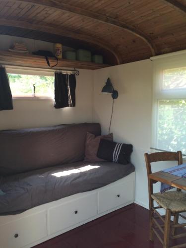 een bed in een kamer met een tafel en een raam bij Gipsy wagon near Amsterdam and beach in Velserbroek 