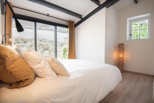 une chambre avec un grand lit blanc avec une fenêtre dans l'établissement Le Jardin de La Tour Pinte, à Carcassonne