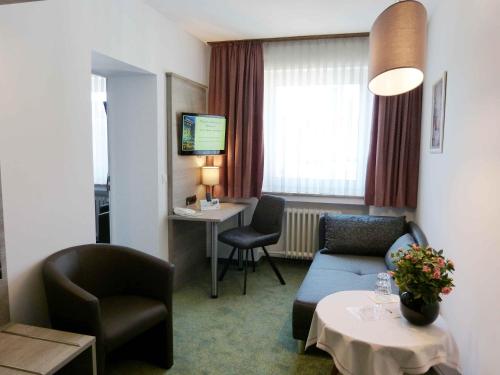 a hotel room with a couch and a table and chairs at Hotel Wurms in Düsseldorf