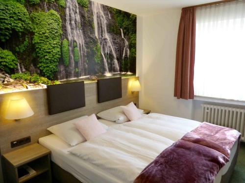 a bedroom with a bed with a painting on the wall at Hotel Wurms in Düsseldorf
