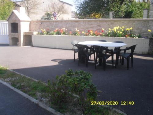 eine Terrasse mit einem Tisch, Stühlen und Blumen in der Unterkunft Maison - Chambre d’hôte située au cœur d Asfeld in Asfeld