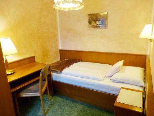 a small bedroom with a bed and a desk and a table at Hotel Wurms in Düsseldorf