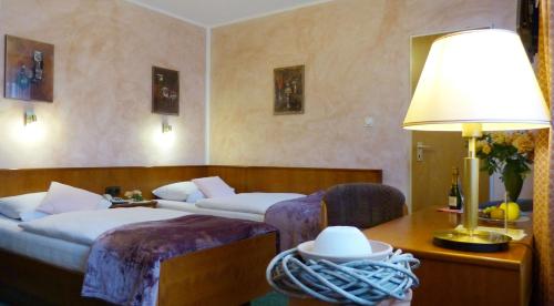 a hotel room with two beds and a table with a lamp at Hotel Wurms in Düsseldorf