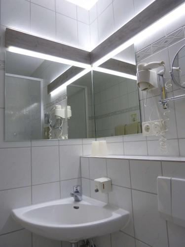 a white bathroom with a sink and a mirror at Hotel Wurms in Düsseldorf