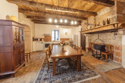 a dining room with a wooden table and a kitchen at Gites chez Antonin in Tour-de-Faure