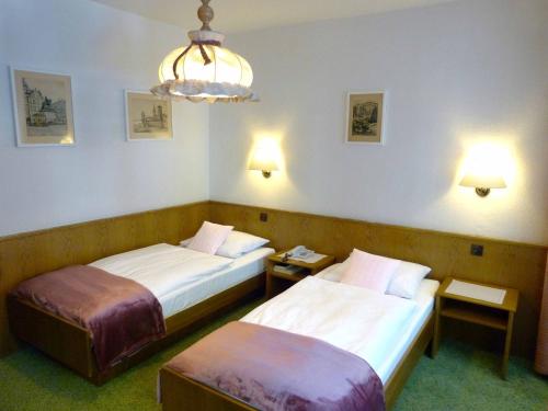 a hotel room with two beds and a chandelier at Hotel Wurms in Düsseldorf