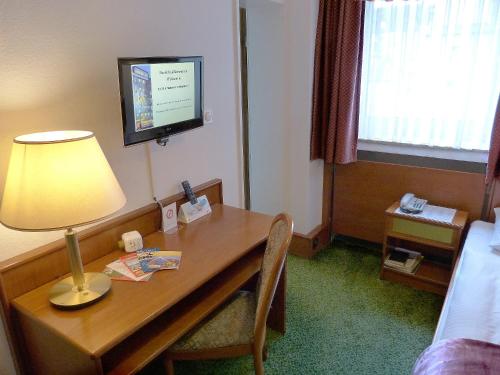 a hotel room with a desk with a lamp and a television at Hotel Wurms in Düsseldorf