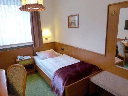 a hotel room with a bed and a mirror at Hotel Wurms in Düsseldorf