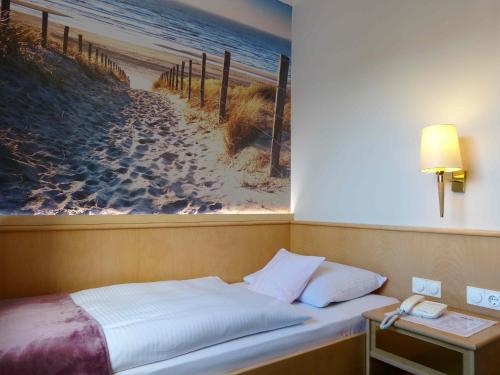 a bed in a room with a picture of a beach at Hotel Wurms in Düsseldorf
