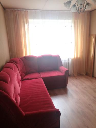 a red couch in a living room with a large window at Mols in Liepāja