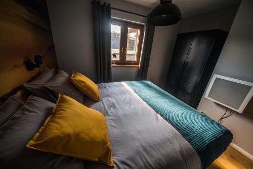 a bedroom with a bed with yellow and green pillows at Krzywe Zwierciadło in Mrągowo