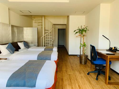 ein Hotelzimmer mit 3 Betten und einem Schreibtisch mit einem Computer in der Unterkunft HiyagunLanaiResort in Okinawa