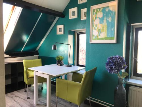 a dining room with green walls and a white table and chairs at Bed&Breakfast Maasland in Maasland