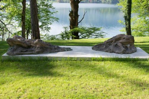 two statues of trees in a park with a lake at Private beach house on Lake Bled in Bled