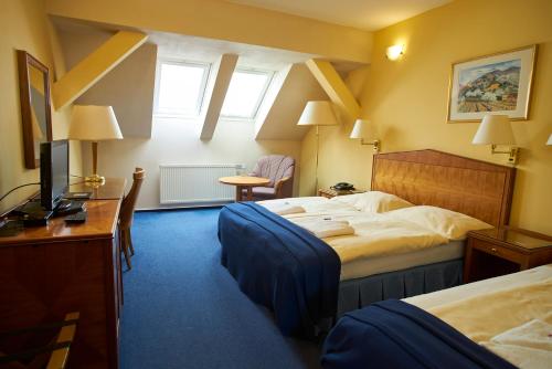 a hotel room with two beds and a television at Hotel Prajer in Vodňany