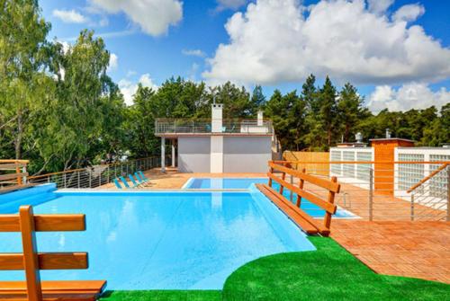 une piscine avec un banc et une maison dans l'établissement Apartament 10B Niebieskie Apartamenty z basenem krytym, odkrytym, salą zabaw, animacjami, à Poddąbie
