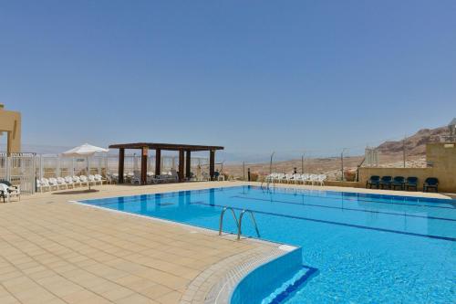 a large swimming pool with chairs and a gazebo at HI - Massada Hostel in Ein Bokek