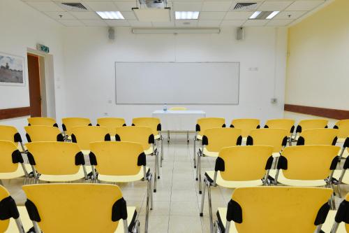 an empty classroom with yellow chairs and a whiteboard at HI - Massada Hostel in Ein Bokek