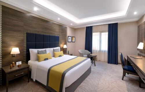 a hotel room with a large bed and a desk at voco Al Khobar by IHG in Al Khobar