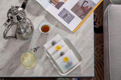 a glass table with a tray and a glass jar of honey at voco Al Khobar by IHG in Al Khobar