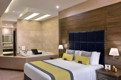 a bedroom with a large bed and a bath tub at voco Al Khobar by IHG in Al Khobar