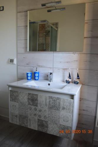 ein Badezimmer mit einem weißen Waschbecken und einem Spiegel in der Unterkunft A mmari semu - Scala dei Turchi in Realmonte
