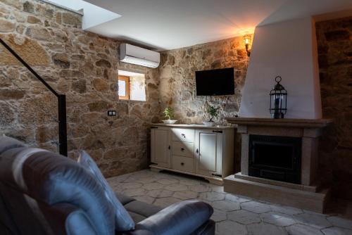 a living room with a fireplace and a tv at Casa de São Miguel in Aldeia de João Pires