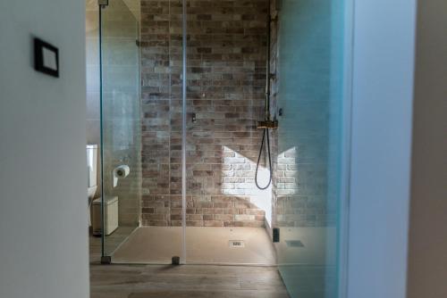 una doccia in vetro in un bagno con parete di mattoni di Casa de São Miguel a Aldeia de João Pires