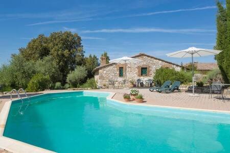 una grande piscina blu davanti a una casa di Podere La Castellina a Podere Poggiaccio