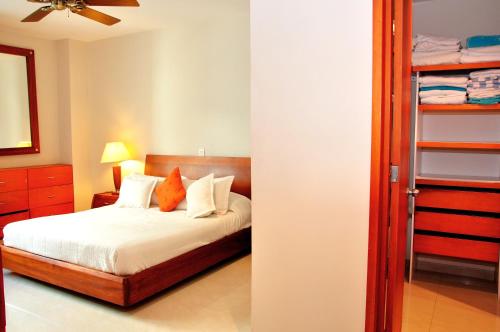 1 dormitorio con 1 cama con sábanas blancas y almohadas de color naranja en Apartamentos Morros Cartagena, en Cartagena de Indias