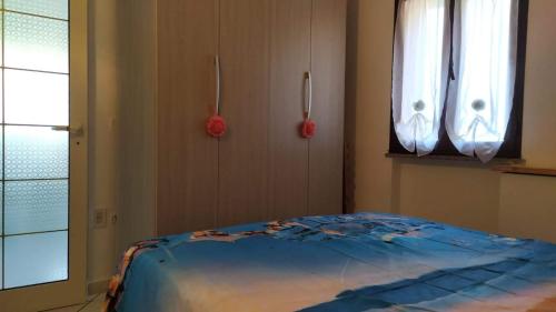 een slaapkamer met een blauw bed in een kamer met ramen bij Casa Vacanza Marco in La Maddalena