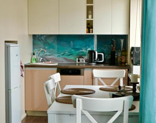 uma cozinha com uma mesa e cadeiras numa cozinha em Neptune Ear, Family-friendly, modern, fully-equipped, cozy apartment em Ventspils