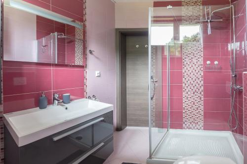 a pink bathroom with a sink and a shower at OPN Apartments Bled in Bled