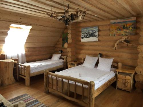 a room with two beds in a log cabin at Будинок Художника Шипіт in Pilipets