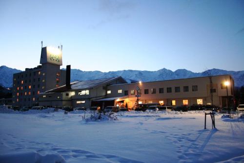 a large building with a clock tower in the snow at Hakuba Highland Hotel in Hakuba